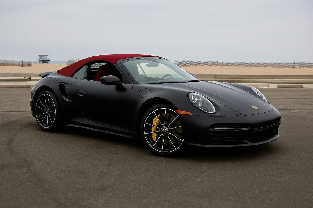 Porsche 911 Turbo S Cabriolet — matte black with red soft top at the beach